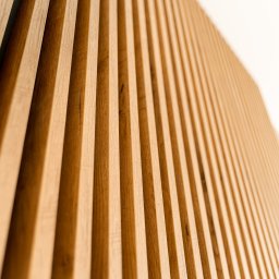 ALEKSANDRA BORAWSKA - Drewniane lamele ścienne w Gdańsku, ułożone pionowo, tworzące dekoracyjny panel. Widok pod kątem, ukazujący strukturę drewna i subtelne cieniowanie.