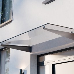 WIZUALIZACJE 3D, ANIMACJE 3D, DRUK 3D, SKAN 3D - Szklany daszek nad wejściem do budynku, wsparty na metalowych wspornikach, z widocznym fragmentem elewacji i okna.