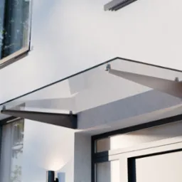 Szklany daszek nad wejściem do budynku, wsparty na metalowych wspornikach, z widocznym fragmentem elewacji i okna.