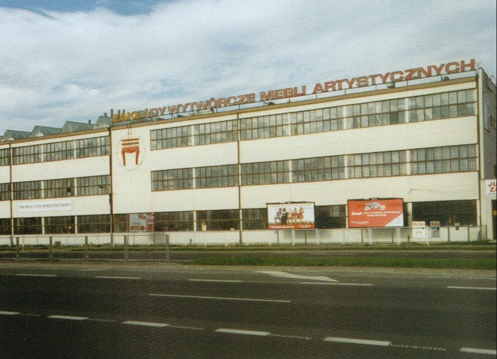 Budynek Zakładów Wytwórczych Mebli Artystycznych z latami produkcji, widok z ulicy, reklamy na ogrodzeniu.