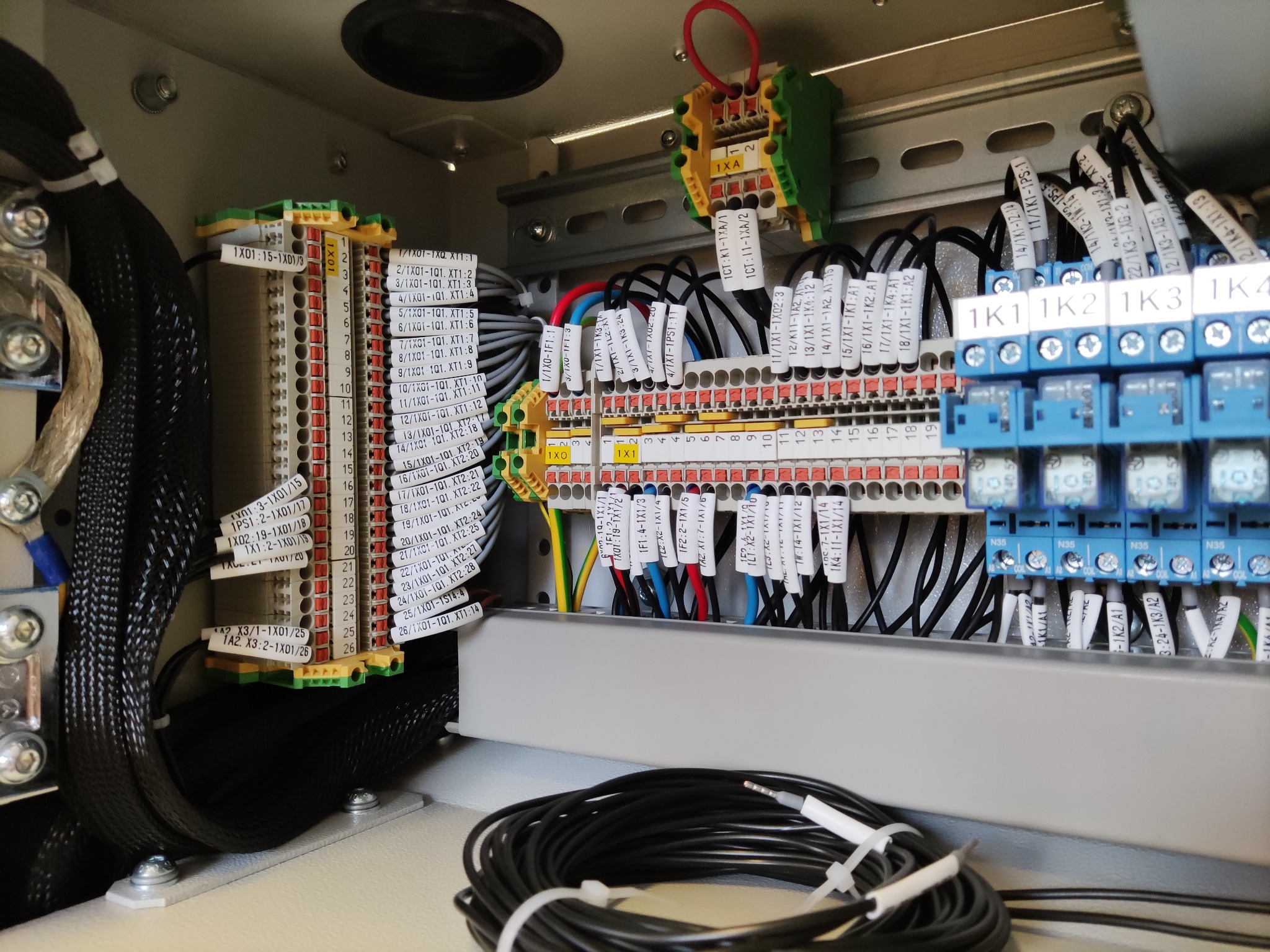 Rozdzielnica elektryczna z precyzyjnie oznaczonymi przewodami i złączkami. Widoczne kable w peszlach i listwy zaciskowe z opisami. Estetyczne i uporządkowane okablowanie.