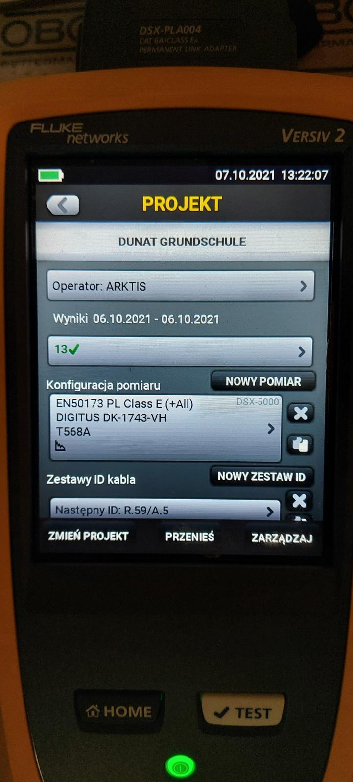 Ekran miernika Fluke Networks Versiv 2 prezentujący wyniki pomiarów kabli w szkole Dunat Grundschule, z konfiguracją pomiaru EN50173 PL Class E (+All) i identyfikatorem kabla R.59/A.5.