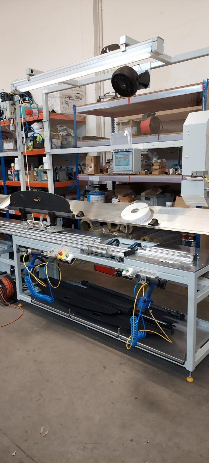 Automatyczna linia produkcyjna z panelem sterowania i narzędziami pneumatycznymi w warsztacie.