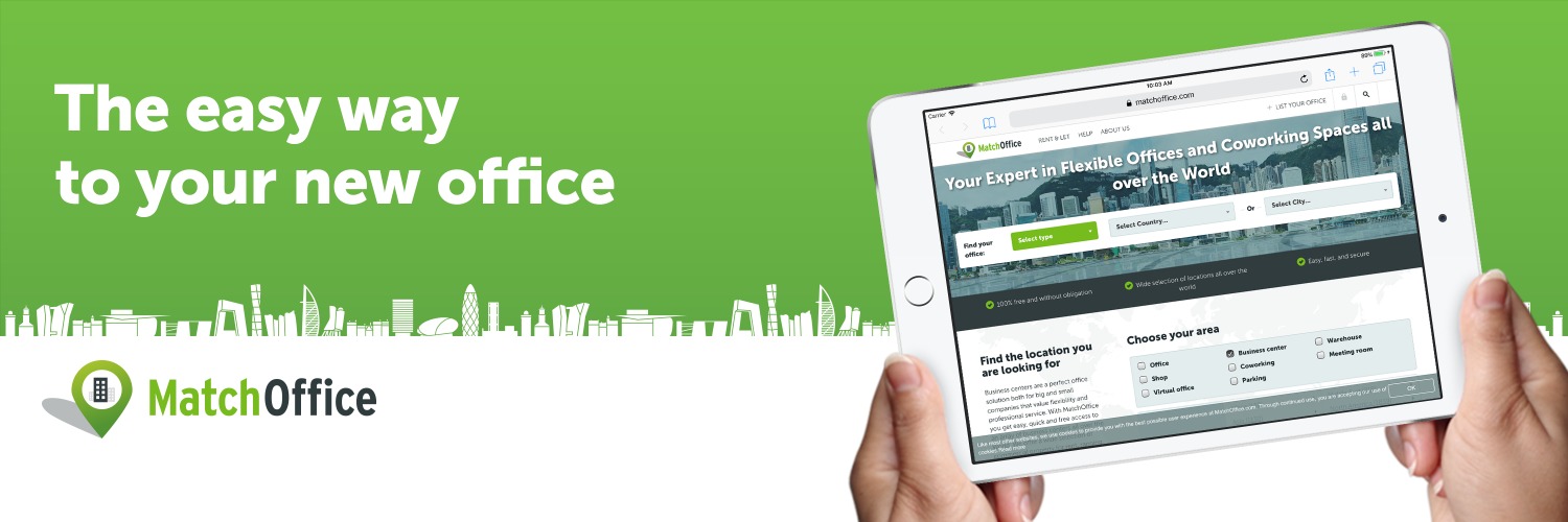 Tablet z aplikacją do wyszukiwania biur na wynajem w Warszawie, trzymany w dłoniach na tle zielonego baneru z hasłem reklamowym.