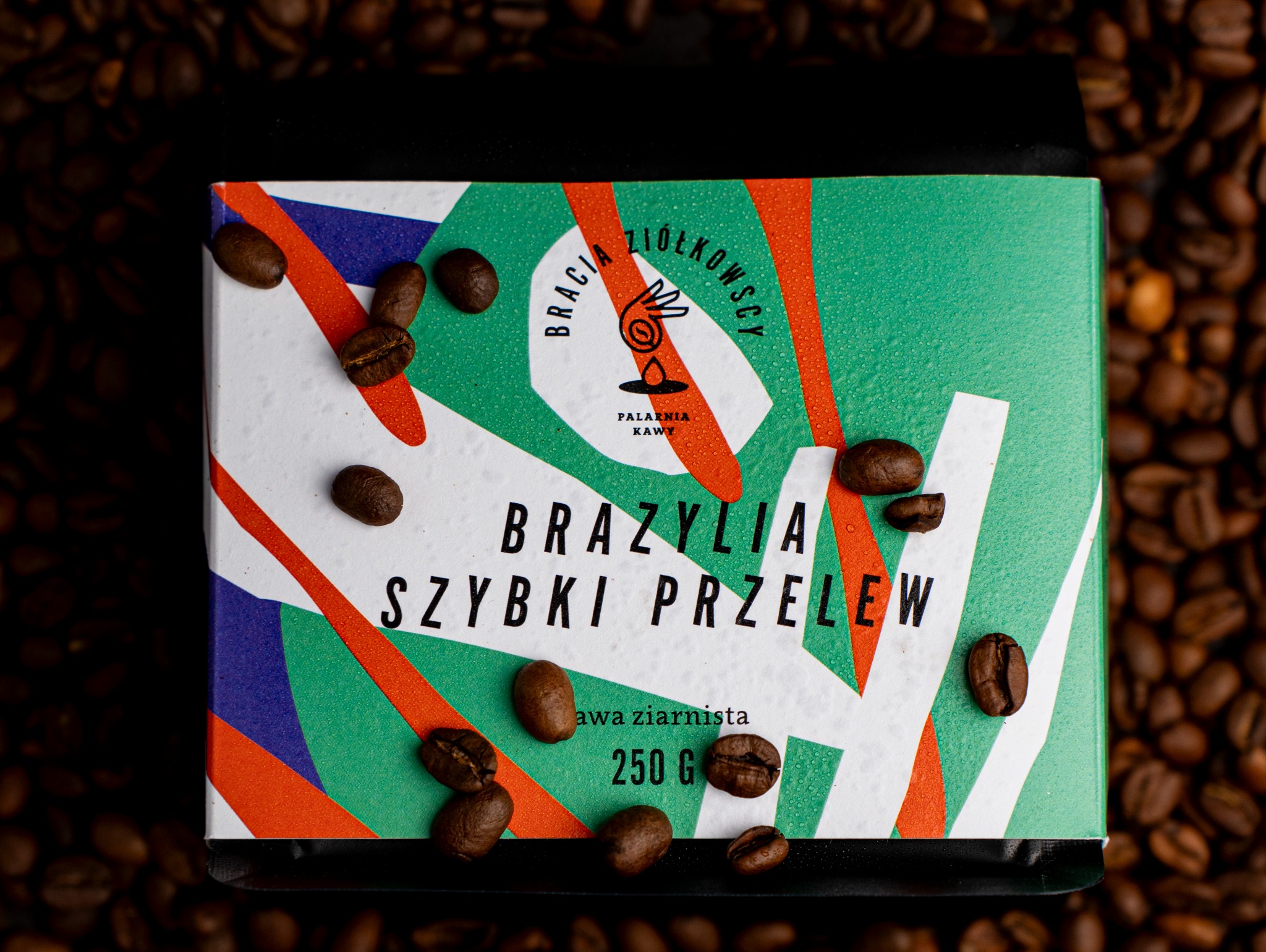 Paczka kawy ziarnistej Brazylia Szybki Przelew z logo Bracia Ziółkowscy Palarnia Kawy, otoczona ziarnami kawy na ciemnym tle.