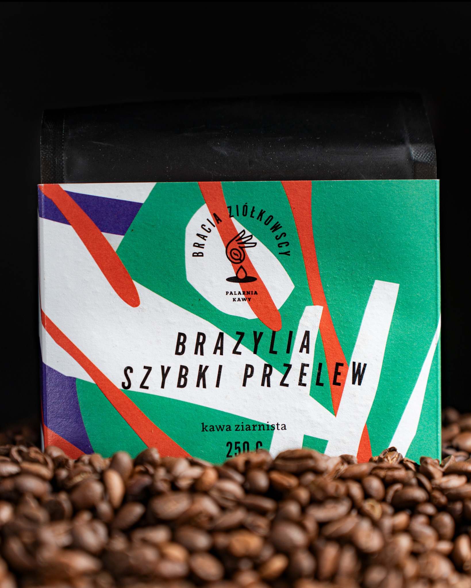 Opakowanie kawy ziarnistej 'Brazylia Szybki Przelew' marki Bracia Ziółkowscy, otoczone ziarnami kawy na czarnym tle.