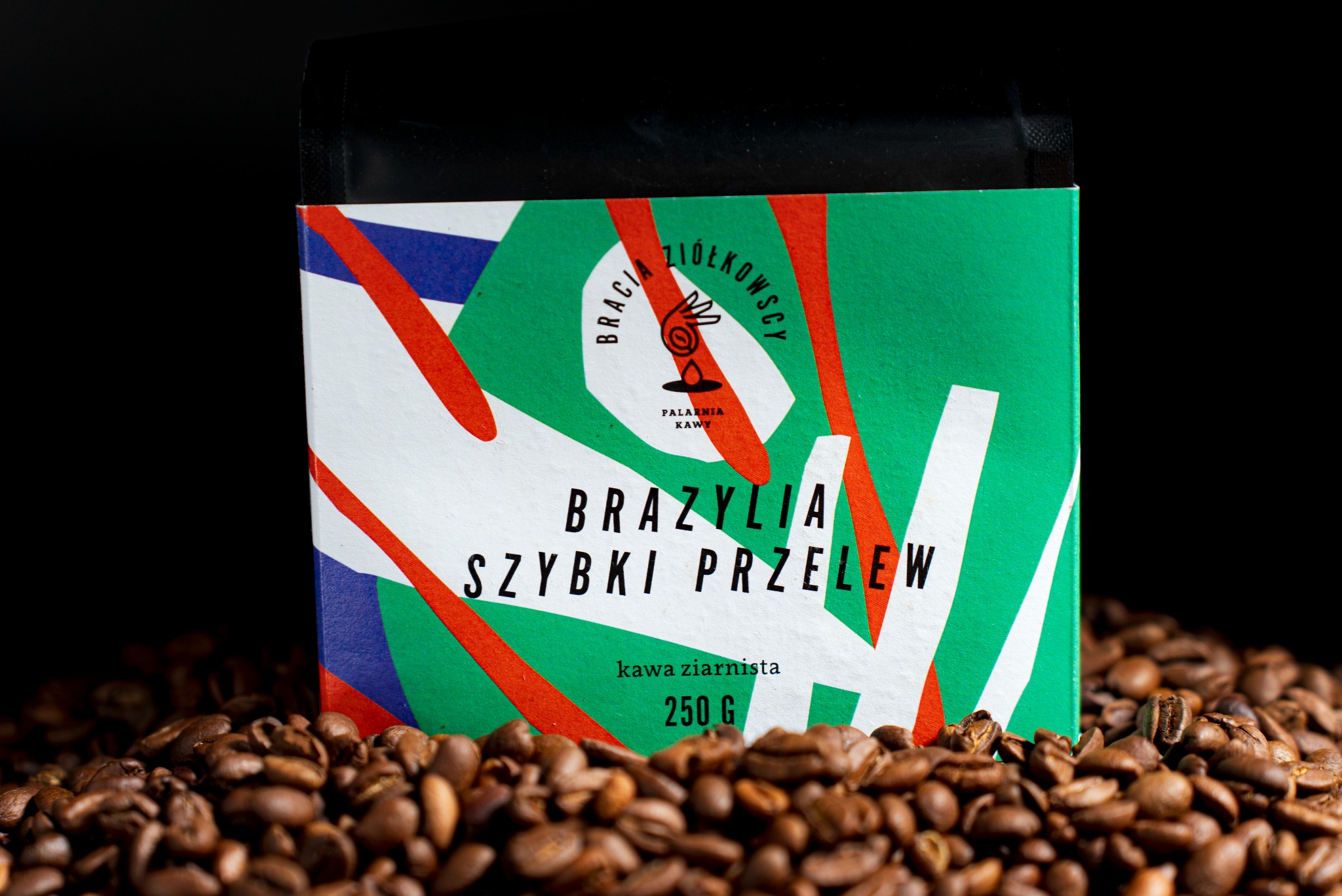 Paczka kawy ziarnistej Brazylia Szybki Przelew 250g Palarnia Kawy Bracia Ziółkowscy, otoczona ziarnami kawy na czarnym tle.