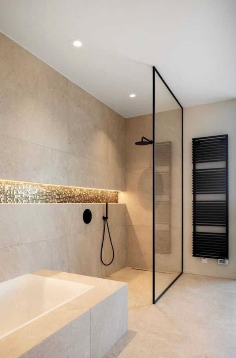 Nowoczesna łazienka z beżowymi płytkami, mozaiką podświetloną LED, czarną armaturą i grzejnikiem drabinkowym, kabina prysznicowa typu walk-in z czarną ramą.