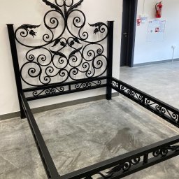 Metalowe Podhale Krzysztof Łowisz - Stelaż łóżka z metaloplastyki w Zakopanem, z dekoracyjnym wezgłowiem i ramą, czarne wykończenie, surowe wnętrze.
