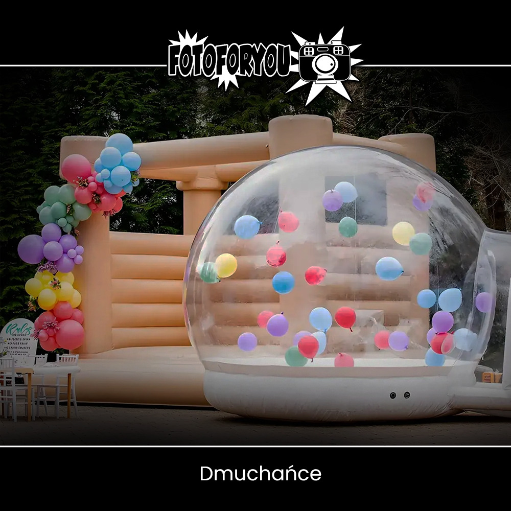 Beżowy zamek dmuchany z dekoracją balonową i przezroczysta kula wypełniona kolorowymi balonami, ustawione na trawniku.