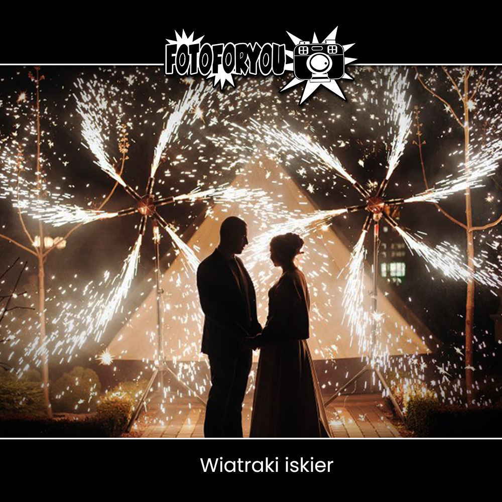 Para Młoda trzymająca się za ręce na tle pirotechniki scenicznej w kształcie wiatraków iskier, oświetlonych od spodu, z logo firmy fotograficznej w górnej części kadru.