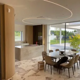 Nowoczesna aranżacja wnętrza domu w Radomiu z otwartą kuchnią, marmurową wyspą, jadalnią z designerskim stołem i krzesłami oraz dekoracyjnym oświetleniem LED.