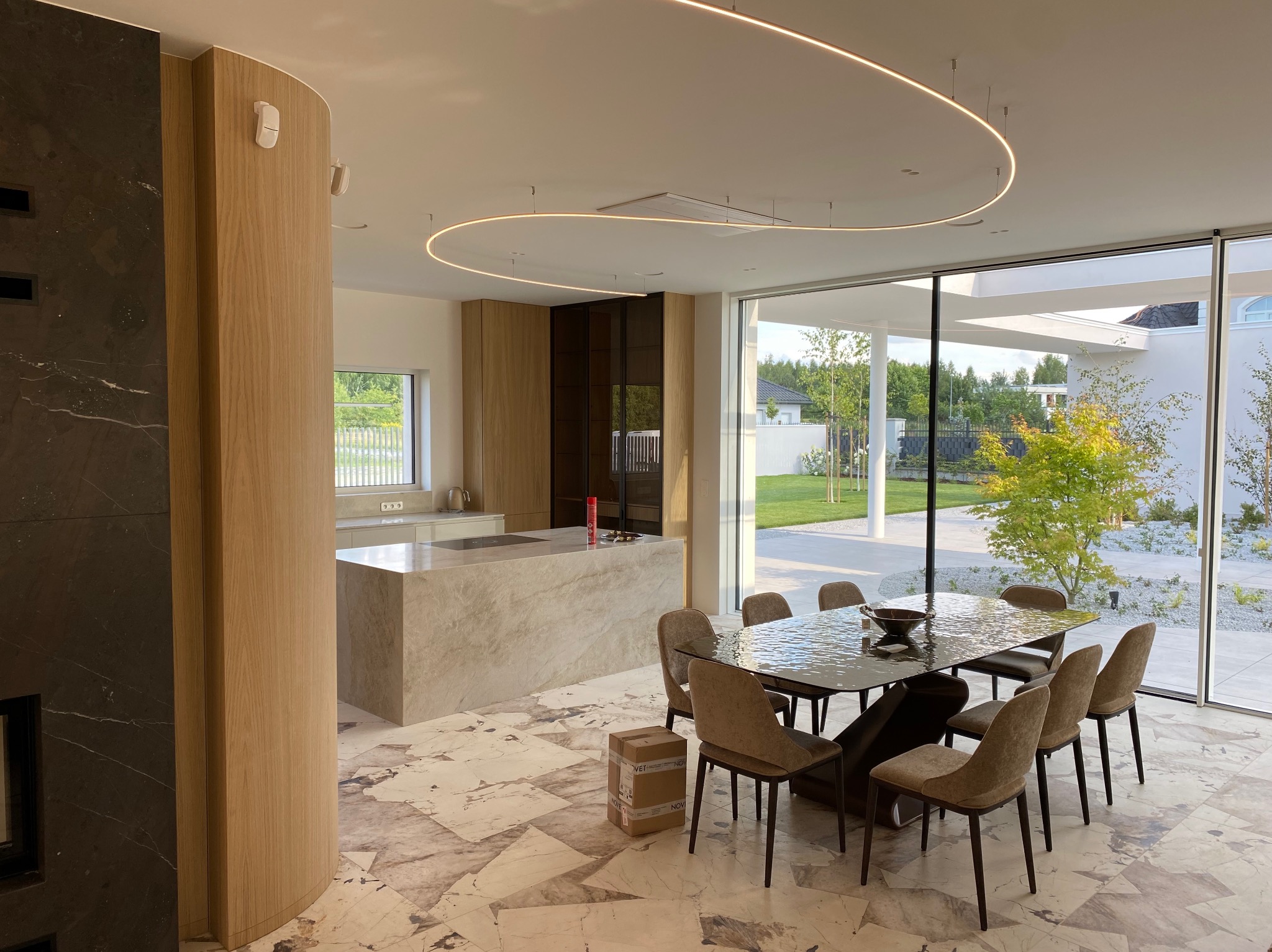 Nowoczesna aranżacja wnętrza domu w Radomiu z otwartą kuchnią, marmurową wyspą, jadalnią z designerskim stołem i krzesłami oraz dekoracyjnym oświetleniem LED.