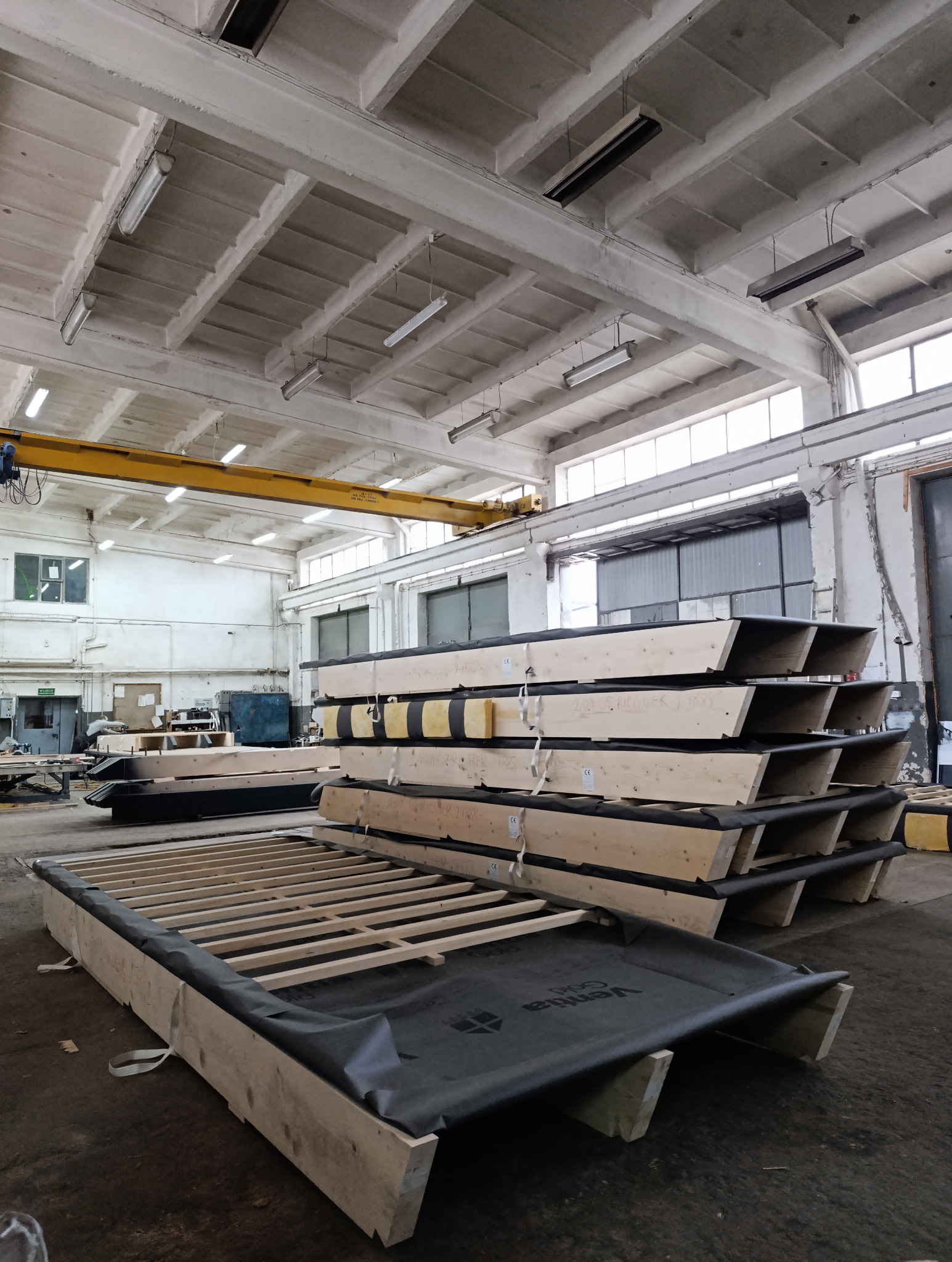 Prefabrykowane elementy konstrukcji dachu i ścian w hali produkcyjnej w Bielsku Podlaskim. Widoczne elementy stropów i wewnętrzne instalacje.