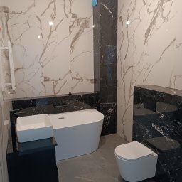 CEGIEŁKA Tomasz Goździela - Elegancka łazienka z marmurowymi płytkami w odcieniach bieli i czerni, wolnostojąca wanna, umywalka nablatowa i podwieszana toaleta. Nowoczesny design.