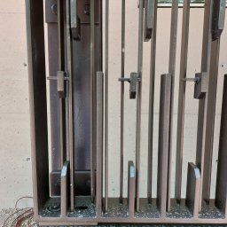 Mobilny Spawacz Jan Bednarczyk Professional Spaw 303 - Metalowa konstrukcja bramy wjazdowej w Warszawie, z widocznymi elementami mocującymi i spawami, na tle betonowej ściany. Detal wykonania.