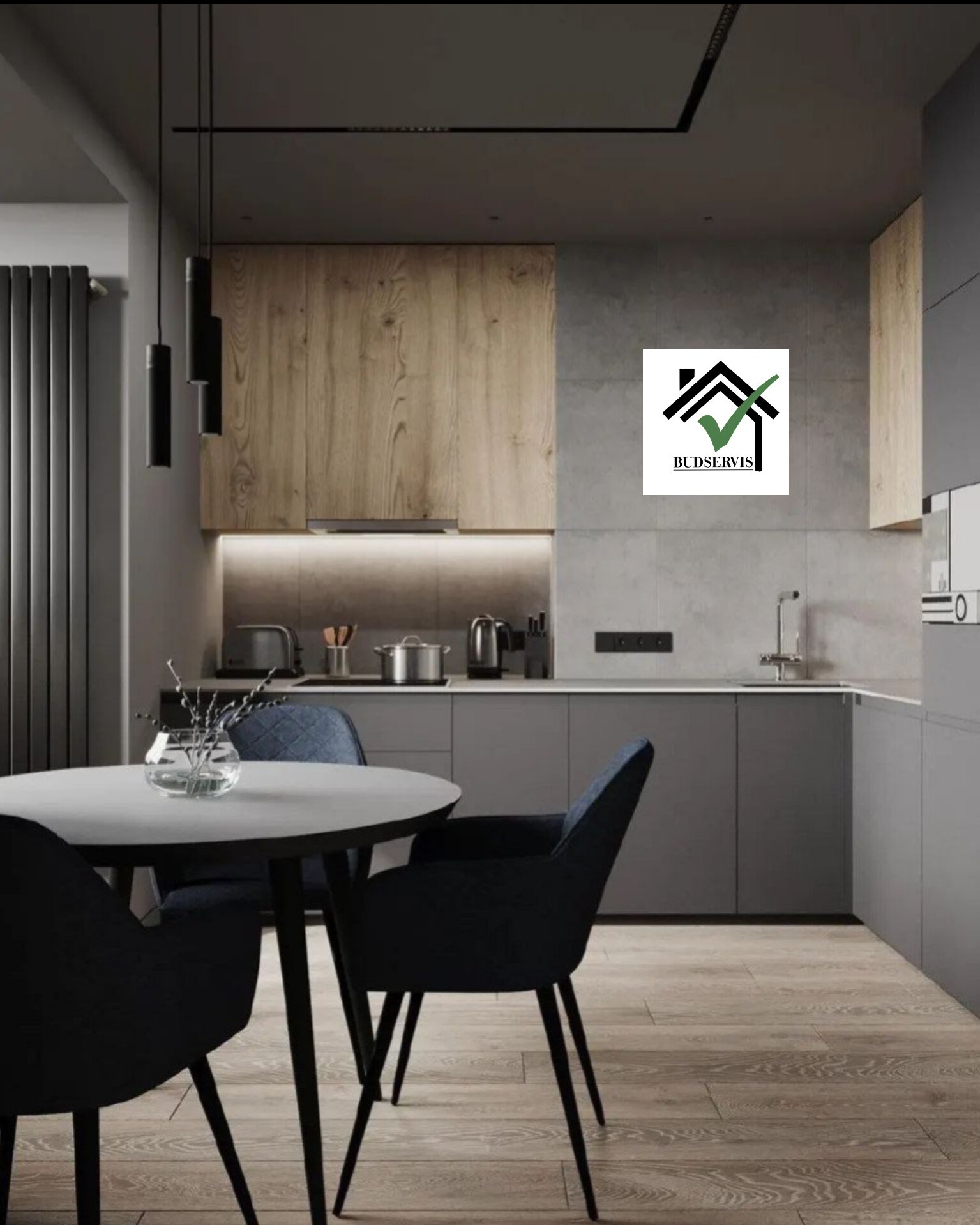 Nowoczesna kuchnia z drewnianymi i szarymi szafkami, okrągłym stołem z ciemnymi krzesłami i minimalistycznym oświetleniem, z logo firmy Budservis w prawym górnym rogu.