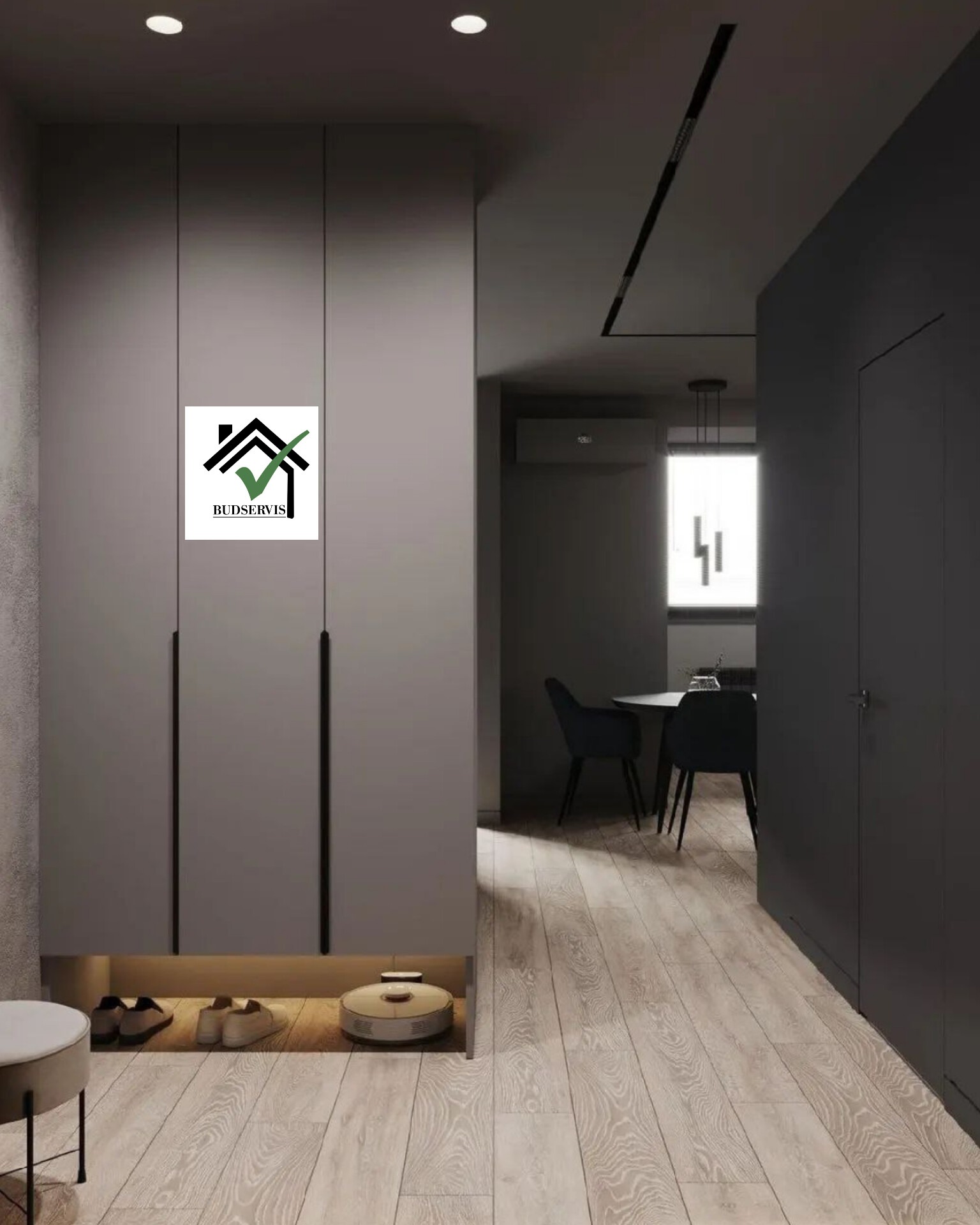 Logo firmy Budservis umieszczone na tle szarej szafy w przedpokoju z widocznym wnętrzem mieszkania i robotem sprzątającym.