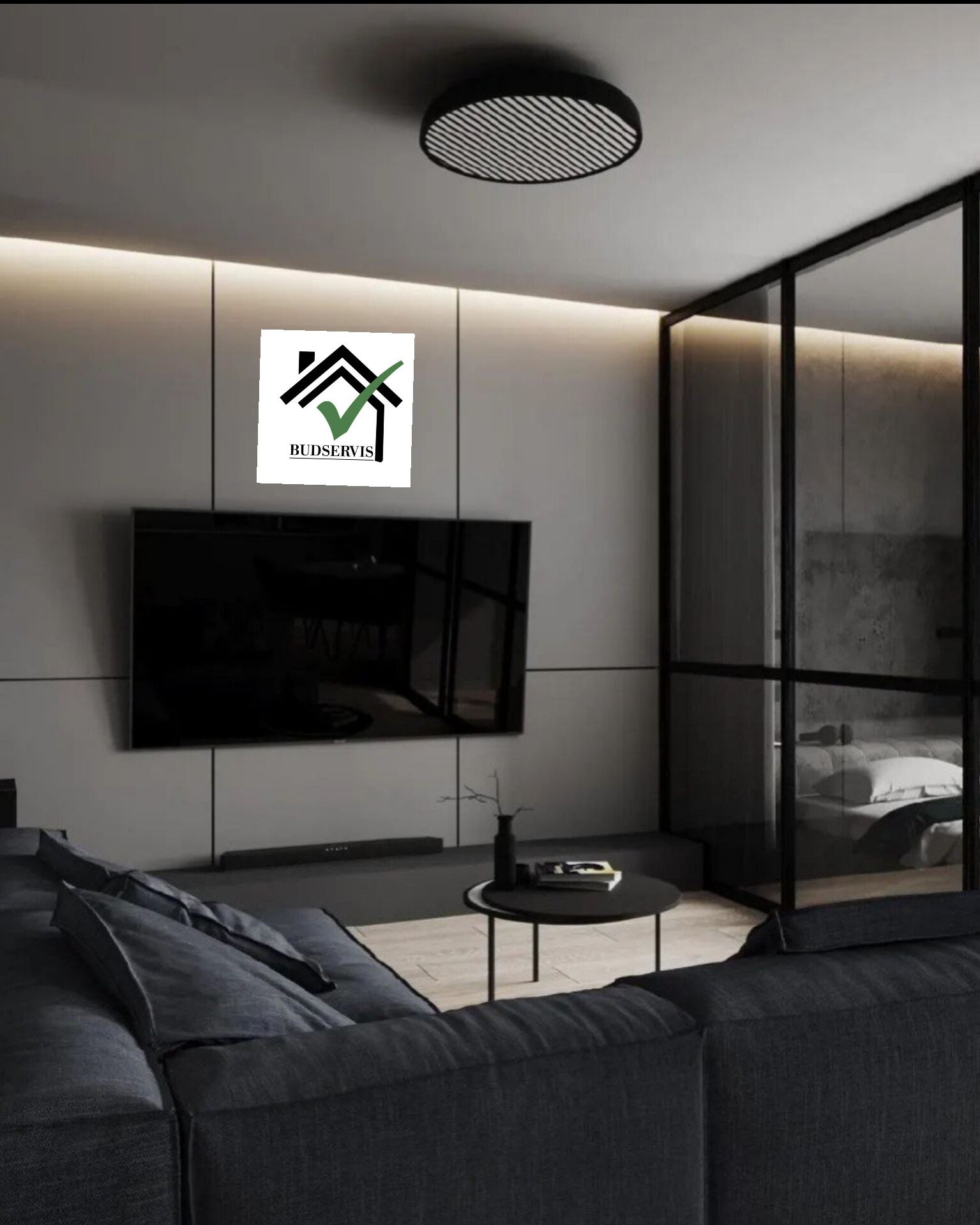Nowoczesny salon z szarą sofą narożną, telewizorem na ścianie i logo firmy Budserwis w rogu kadru.