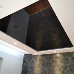 Grzegorz Wojdyła Gregor Bau - Wykończone wnętrze z dekoracyjną szpachlą na ścianie i suficie, oświetlenie punktowe LED w podwieszanym suficie, widok z dołu.