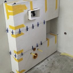 Grzegorz Wojdyła Gregor Bau - W trakcie tworzenia zabudowy geberit z płyt karton-gips w Łobozew Górny, widoczne taśmy, poziomica oraz wiadro z zaprawą.