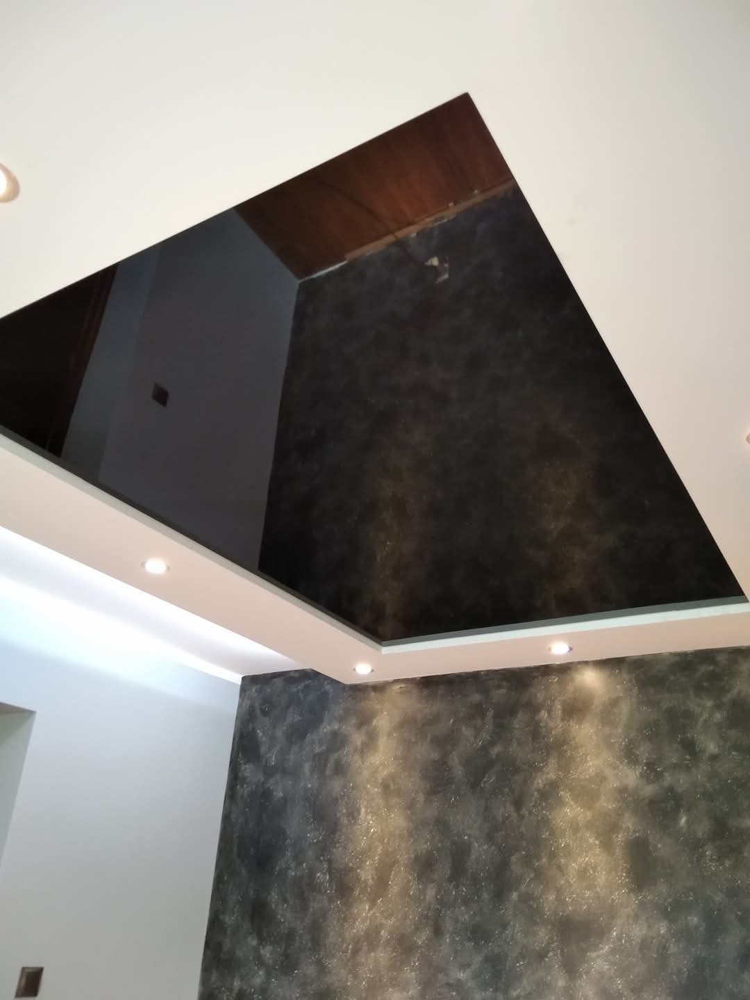 Wykończone wnętrze z dekoracyjną szpachlą na ścianie i suficie, oświetlenie punktowe LED w podwieszanym suficie, widok z dołu.