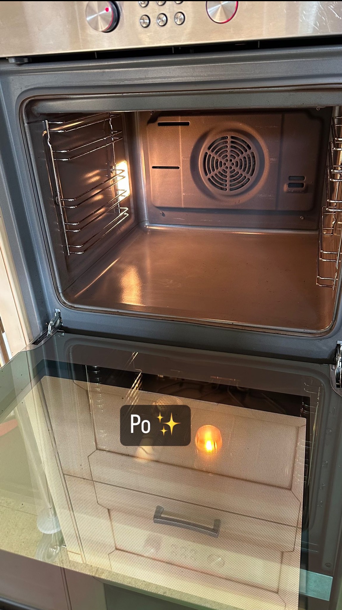 Wnętrze piekarnika po czyszczeniu, widoczne metalowe drabinki i tylna ściana z wentylatorem, wnętrze oświetlone, na szybie naklejony napis 'Po'.