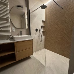 Pavlo Zhosan - Nowoczesna łazienka z kabiną prysznicową typu walk-in, umywalką nablatową na drewnianej szafce i dekoracyjną ścianą z płytek o geometrycznym wzorze w odcieniach brązu.