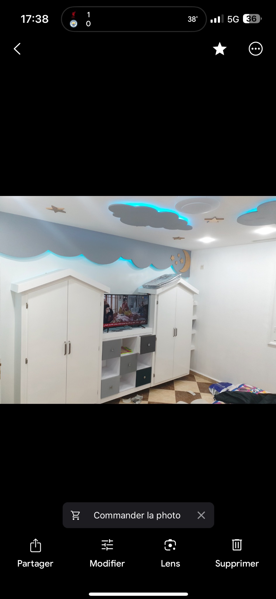 Pokój dziecięcy z zabudową meblową w kształcie domków, podświetlanymi chmurami na suficie i dekoracjami w postaci gwiazd i księżyca.