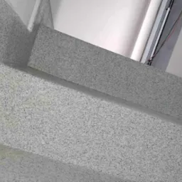 Schody wykończone szarą, nakrapianą powłoką, prawdopodobnie na bazie cementu, z widocznymi niedoskonałościami w narożnikach i krawędziach.