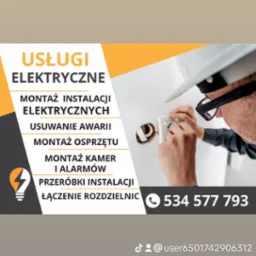 Mężczyzna w okularach i białym kasku montuje białe gniazdko elektryczne w ścianie.