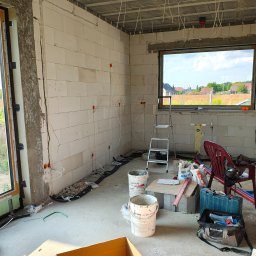 BarTech - Surowy stan: instalacja elektryczna w budynku z betonu komórkowego. Kable wyprowadzone ze ściany, puszki instalacyjne. Widoczna drabina i narzędzia.