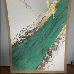 Abstrakcyjny obraz z zielonymi i złotymi akcentami, imitujący marmur, w brązowej ramie, na tle podłogi z paneli. Wyjątkowa faktura i połyskujące detale.