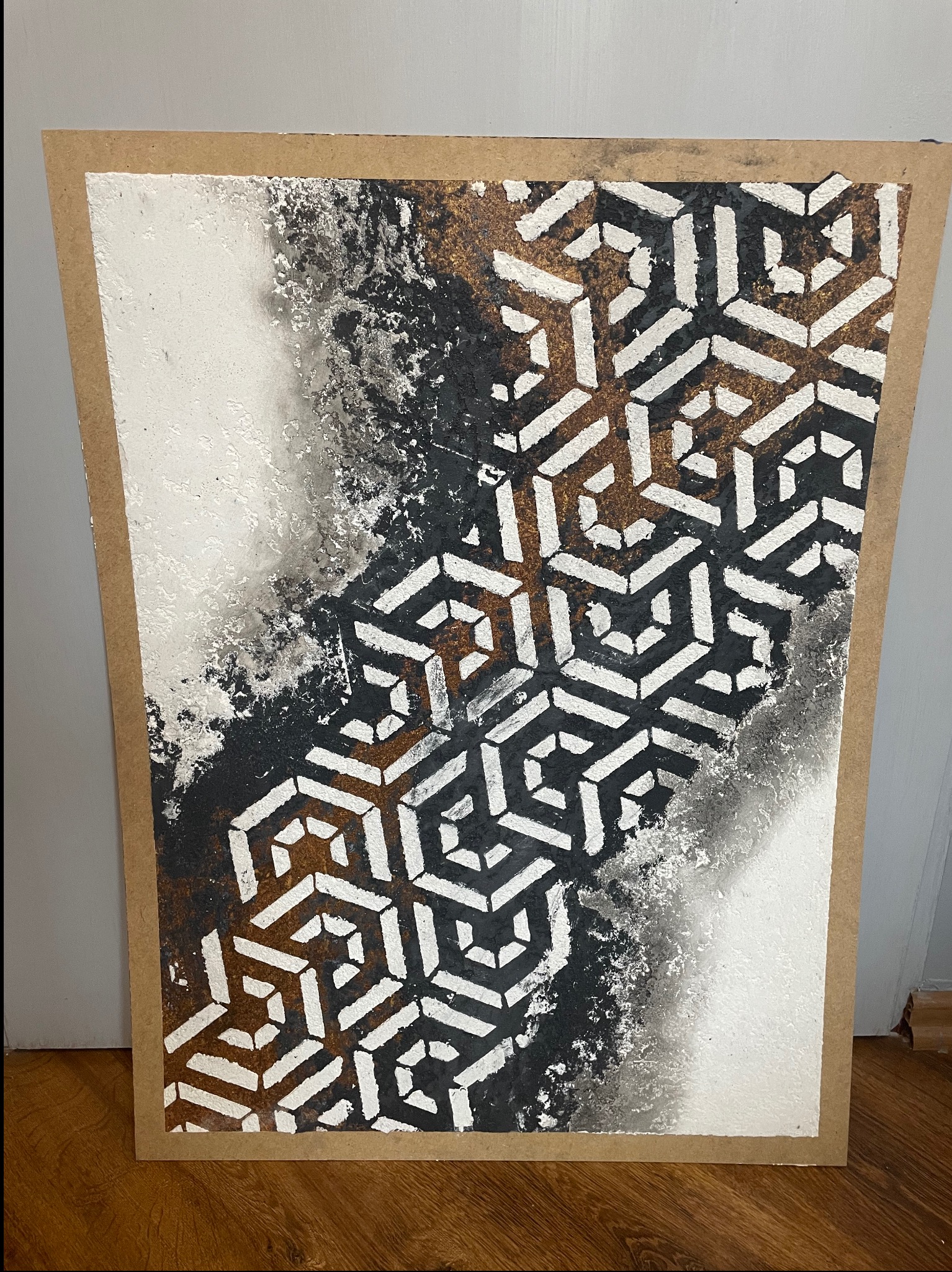 Panel dekoracyjny ze wzorem geometrycznym w odcieniach bieli, czerni i brązu, umieszczony na płycie MDF. Widoczne nieregularne krawędzie wzoru i tekstura farby.