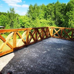 BARWOOD CIESIELSTWO PAWEŁ BARANOWSKI - Drewniana balustrada tarasu z widokiem na bujną zieleń drzew, betonowa posadzka tarasu z widocznymi śladami użytkowania, fragment narzędzia w rogu kadru.