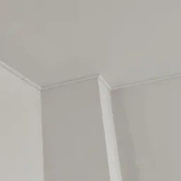 Jasne wnętrze po malowaniu, widoczne połączenie ściany z sufitem z ozdobną listwą przysufitową w narożniku.