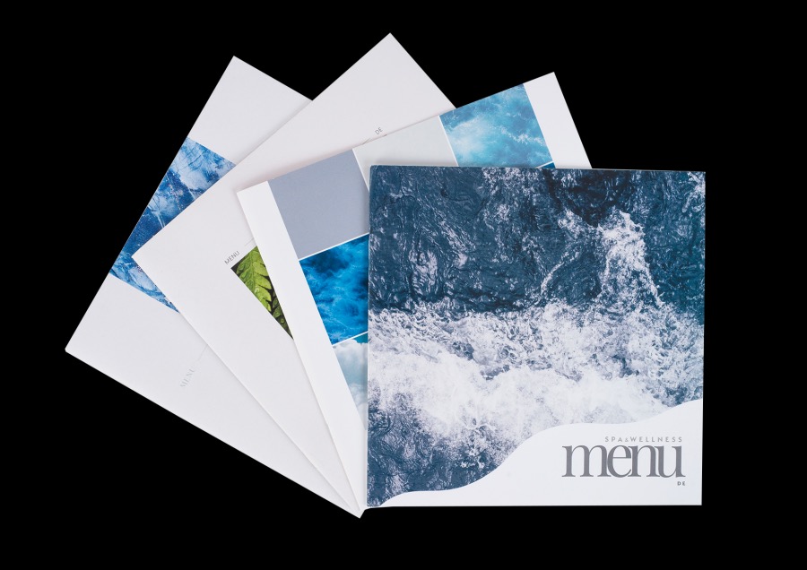 Stos menu SPA & Wellness z motywami wody i natury, ułożonych wachlarzowo na czarnym tle, z widocznym logo.