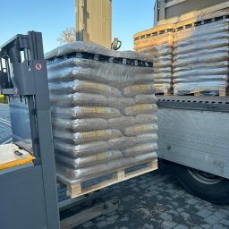 Skład Opału Klikawa TJ MOBILE Sp. z o.o. - Wózek widłowy podnosi paletę z workami pelletu marki Verba Premium, widoczna naczepa ciężarówki w trakcie rozładunku.
