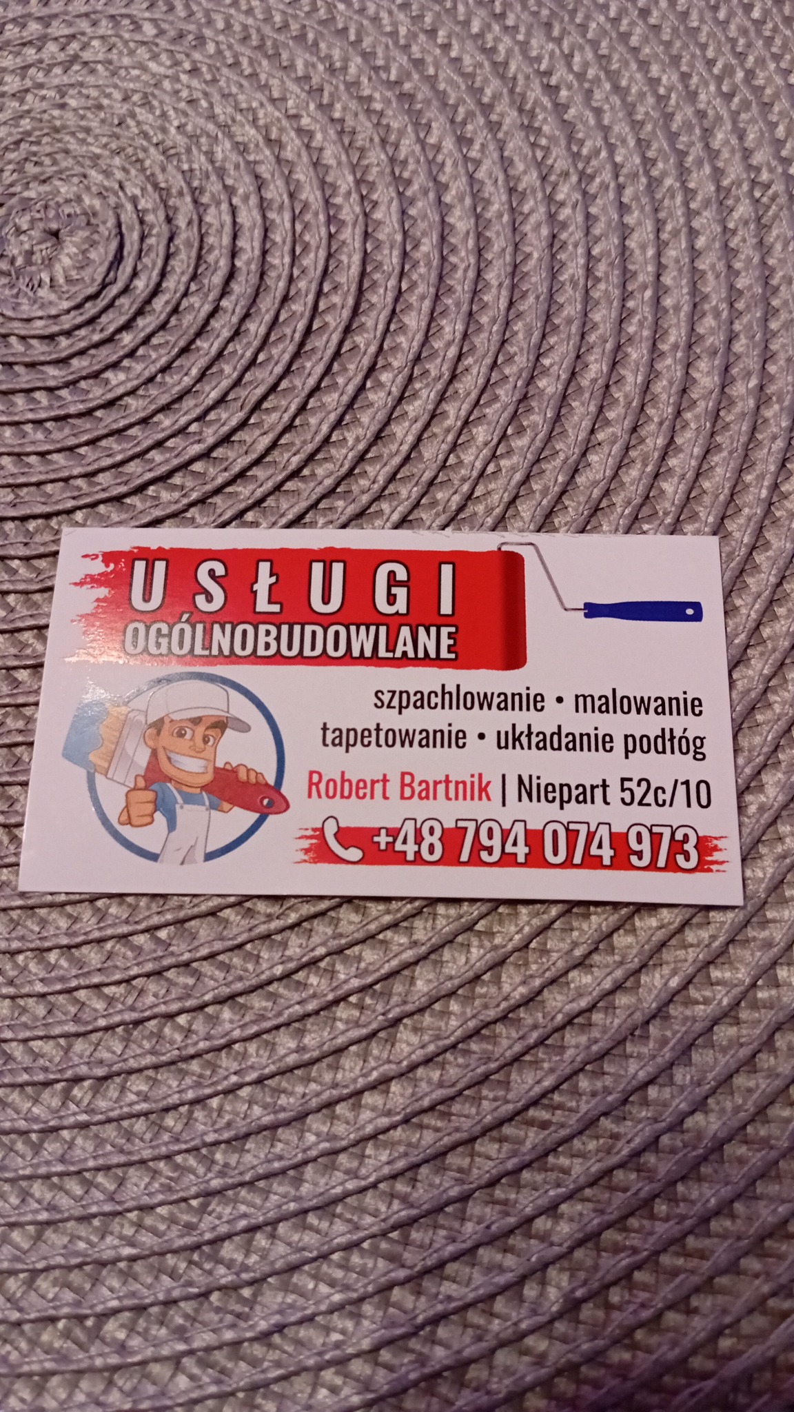 Wizytówka firmy remontowo-budowlanej Roberta Bartnika z listą usług: szpachlowanie, malowanie, tapetowanie, układanie podłóg i danymi kontaktowymi na tle plecionego podkładu.