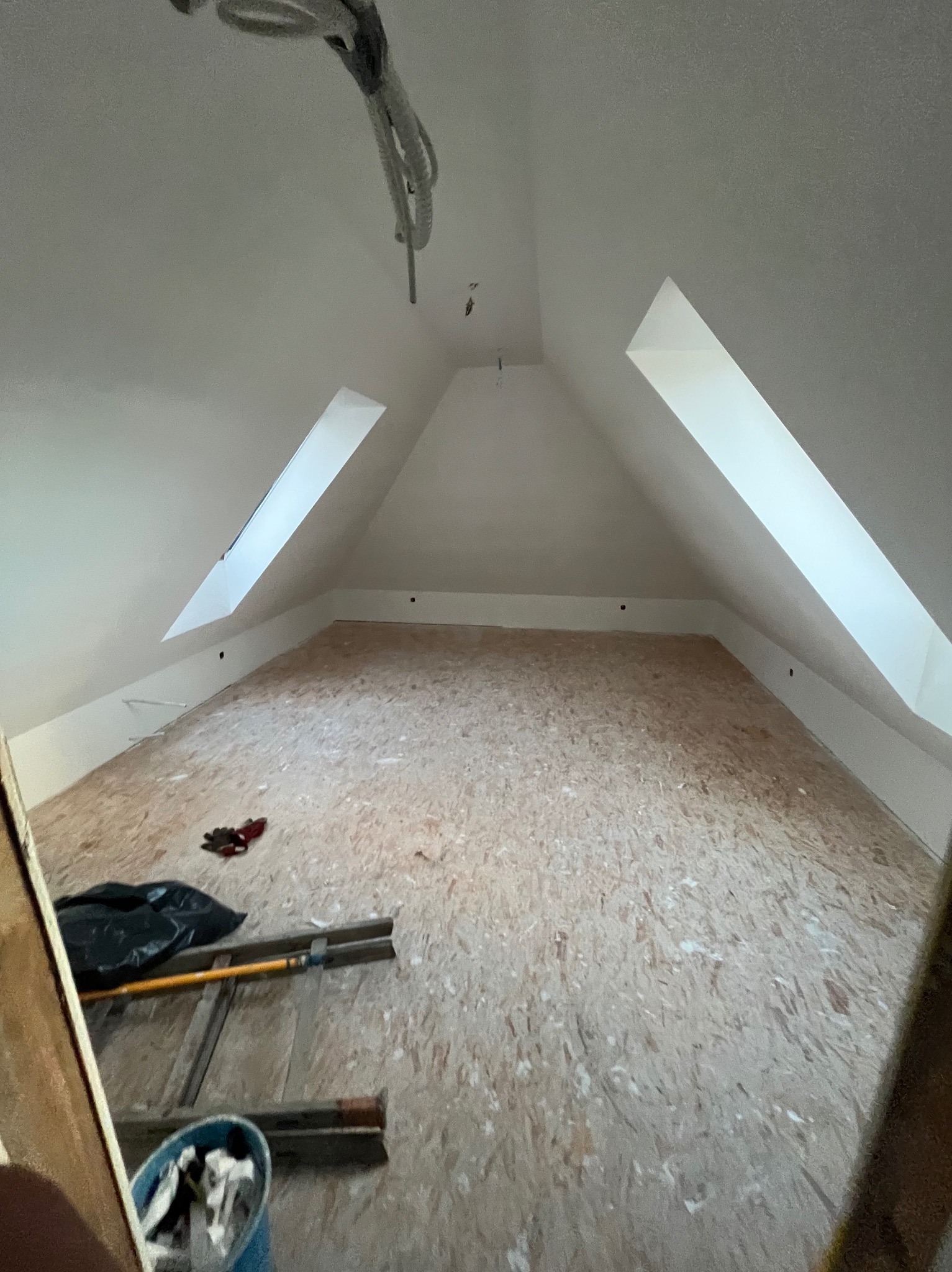 Poddasze w Bielsku-Białej w trakcie adaptacji: widoczne okna dachowe, płyta OSB na podłodze, drabina, narzędzia i instalacja elektryczna.