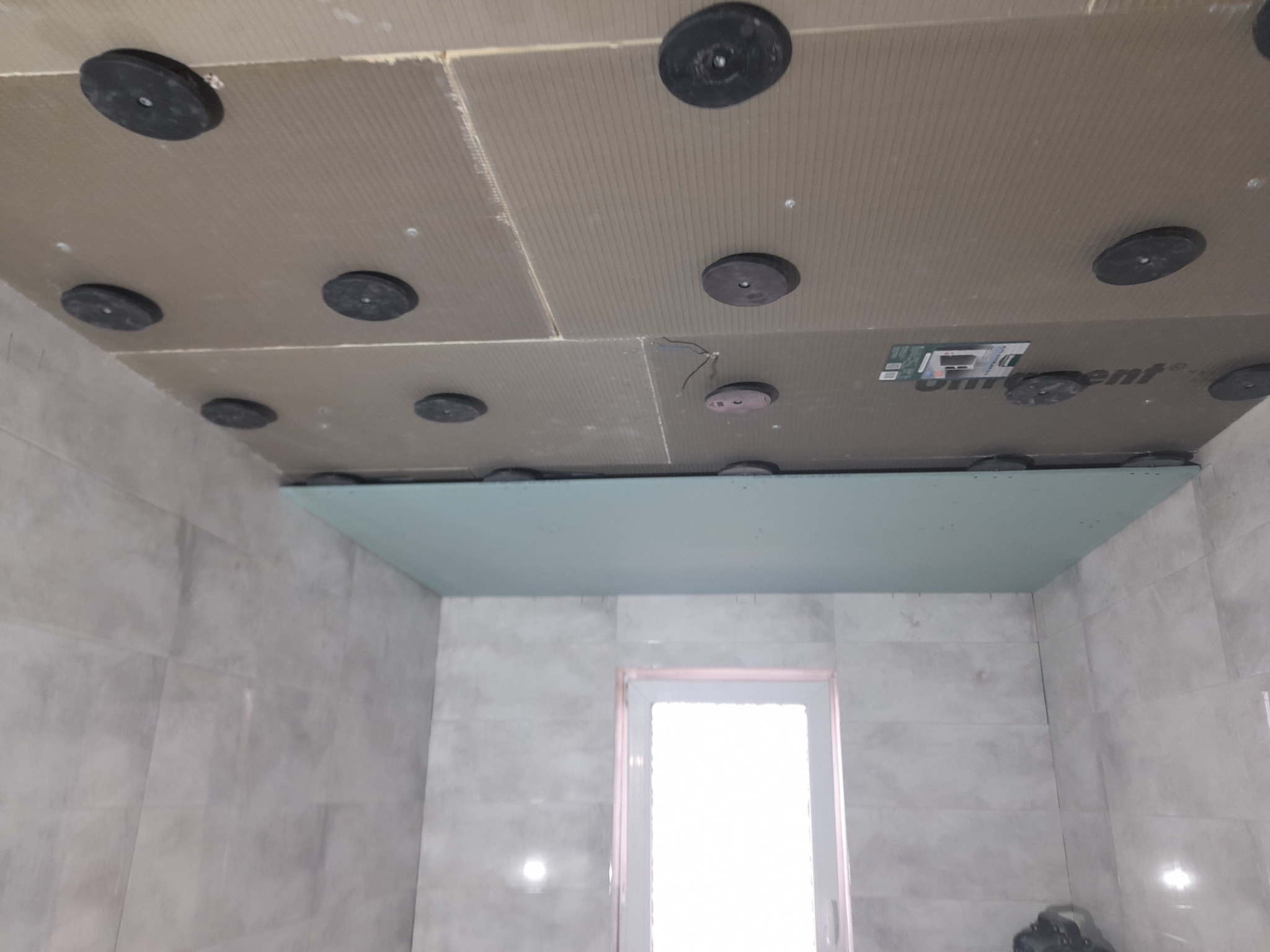 Montaż sufitu podwieszanego z płyty karton gips w łazience z widocznymi elementami mocującymi i izolacją akustyczną.