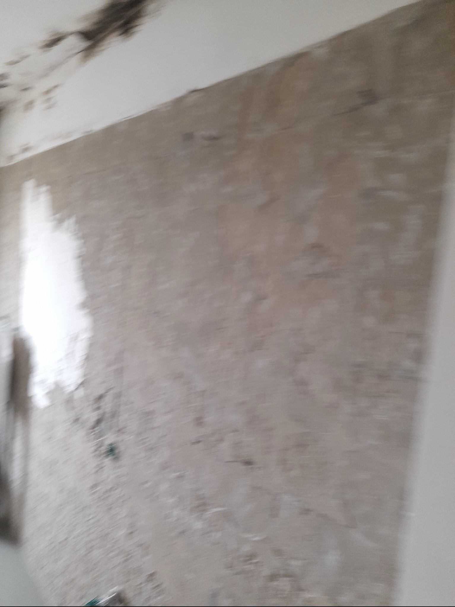 Ściana w trakcie prac przygotowawczych do wykończenia w Mniowie, widoczne ślady po zagruntowaniu i częściowo nałożona warstwa wyrównująca.