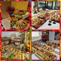 Bogato zastawione stoły z różnorodnymi przekąskami, owocami i dekoracjami kwiatowymi, prezentujące ofertę cateringową z logo firmy na dekoracji.