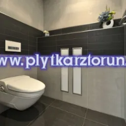 Nowoczesna łazienka z podwieszaną toaletą, szarymi i czarnymi płytkami oraz ukrytą spłuczką, wykończona listwami dekoracyjnymi.