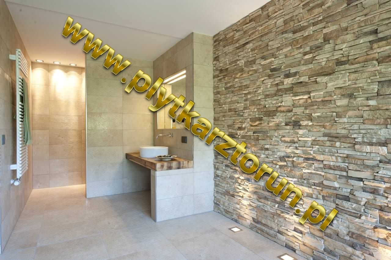 Nowoczesna łazienka z akcentem kamiennej ściany, umywalką nablatową na drewnianym blacie i oświetleniem podłogowym.