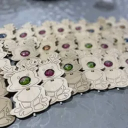 Ręcznie robione drewniane renifery z cukierkami zamiast nosa, leżące na szarym tle.