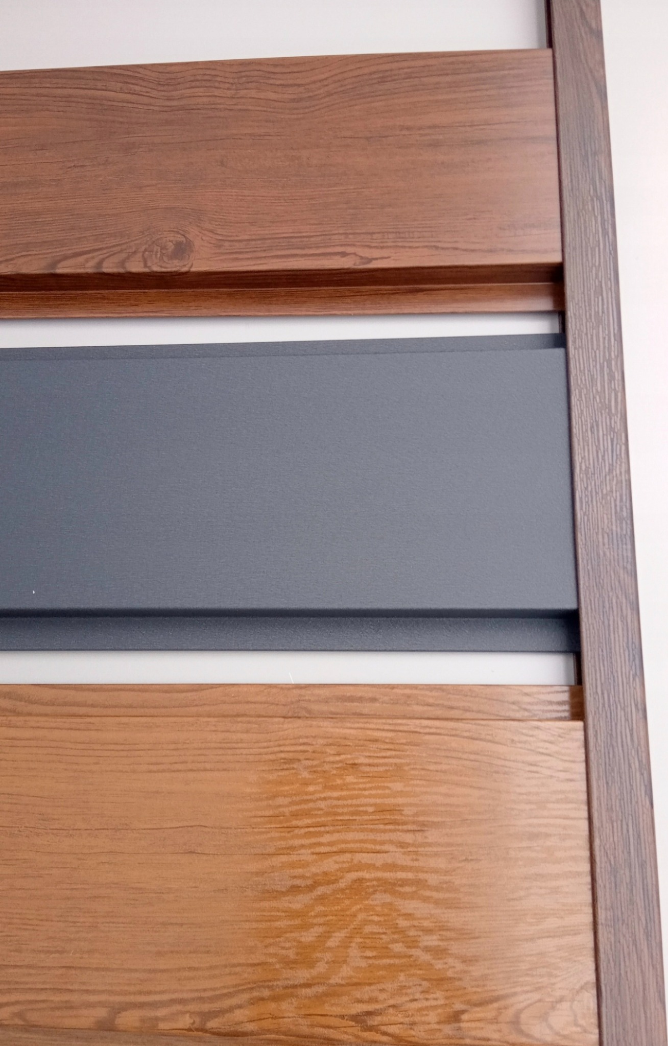 Fragment nowoczesnego ogrodzenia panelowego z drewnopodobnym wykończeniem i szarymi wstawkami, widok z bliska, podkreślający fakturę materiałów.