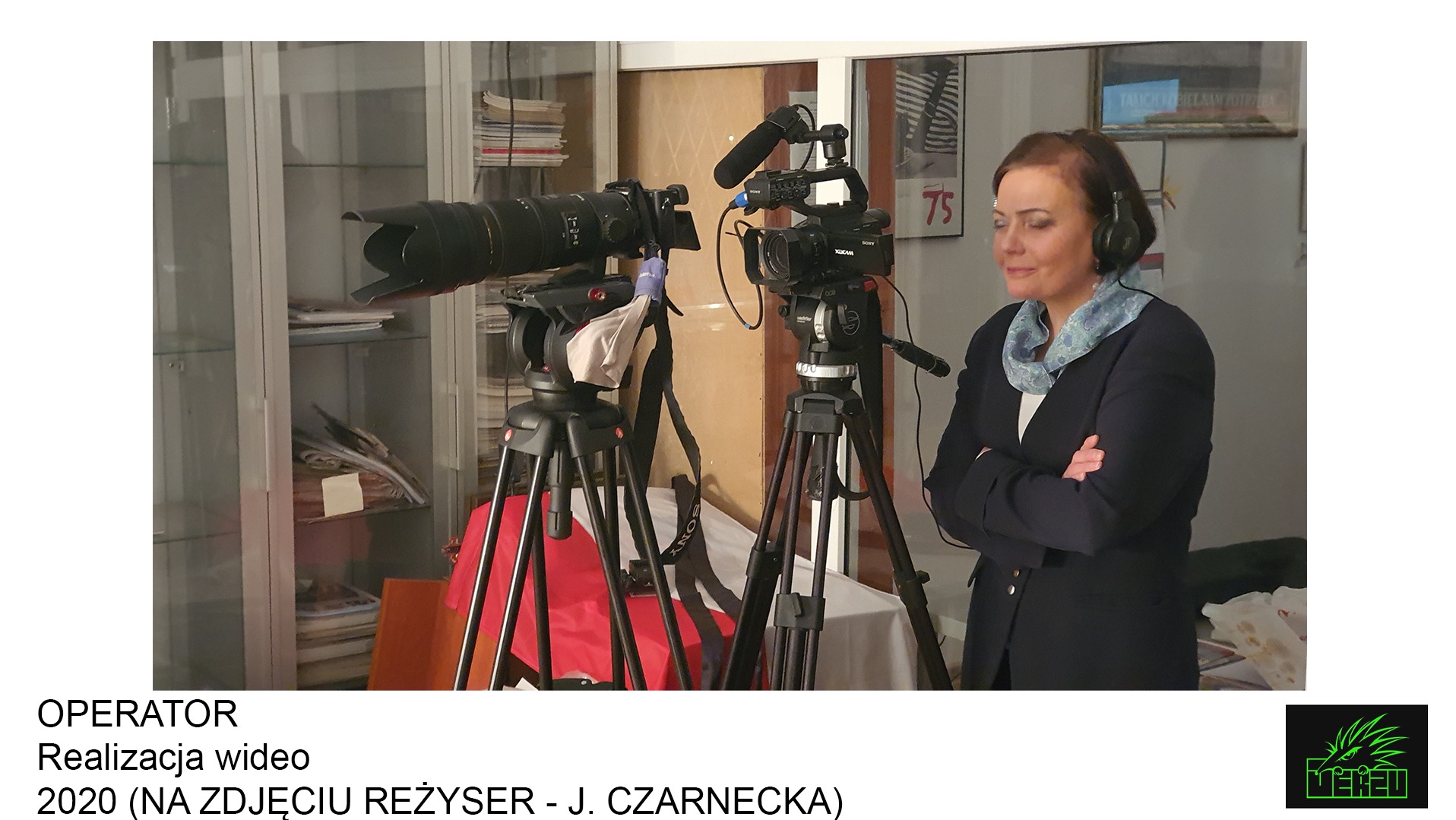 Reżyserka J. Czarnecka w słuchawkach, obserwująca pracę dwóch kamer na statywach z mikrofonami w pomieszczeniu z meblami.