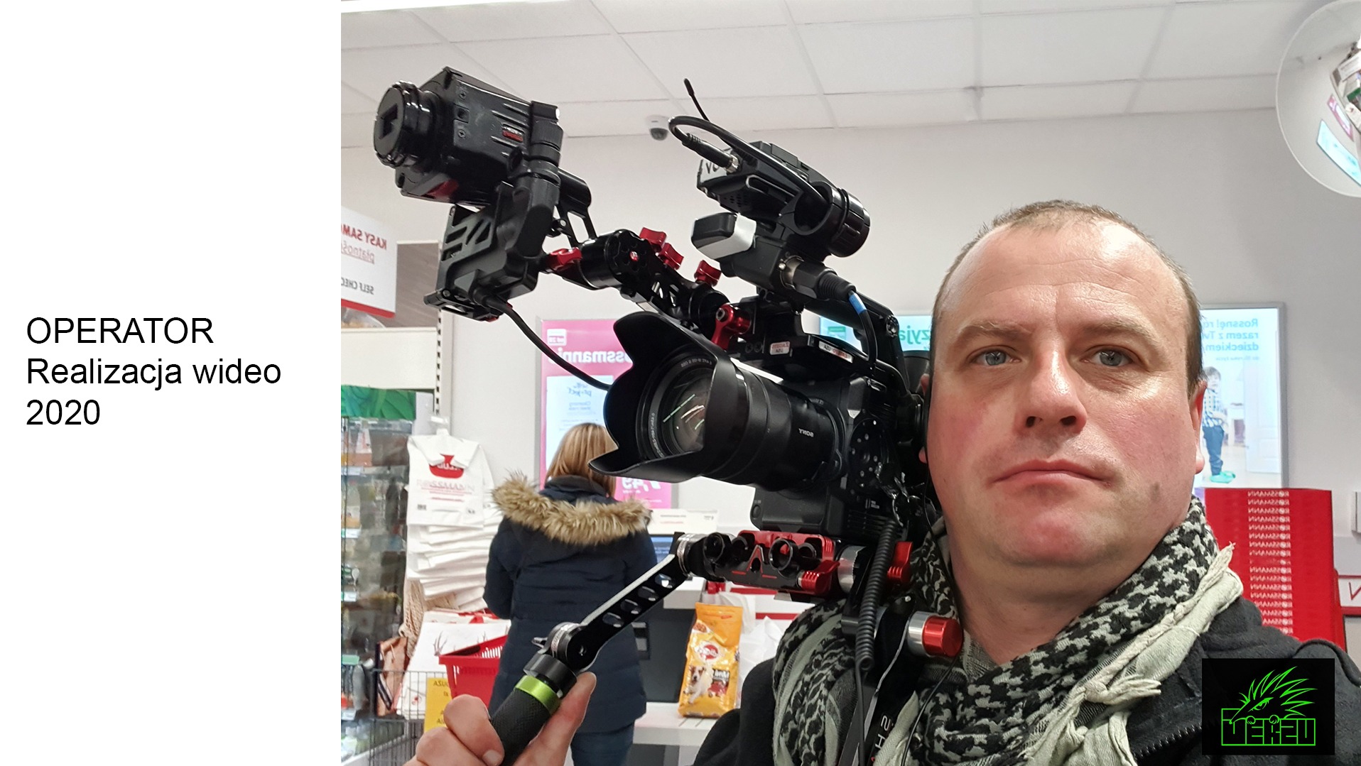 Kamerzysta z profesjonalnym sprzętem w sklepie, widoczna kamera Sony z osprzętem, monitor i mikrofon, mężczyzna z szalikiem w czarno-białe wzory patrzy w obiektyw.