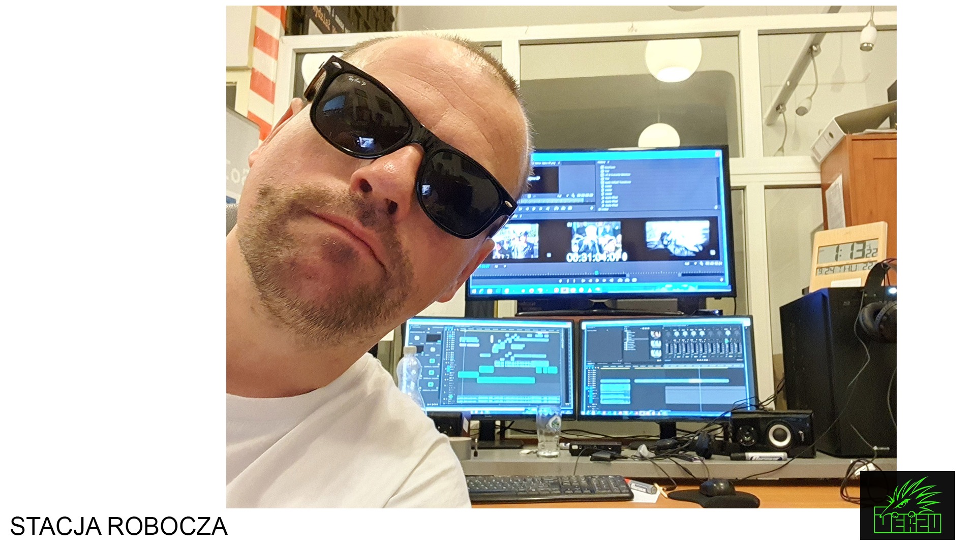 Mężczyzna w okularach przeciwsłonecznych, z bliska, na tle stanowiska pracy z trzema monitorami z oprogramowaniem do edycji wideo i audio.